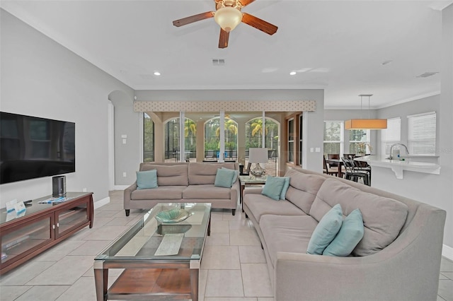 living room featuring crown molding, light tile patterned floors, and ceiling fan