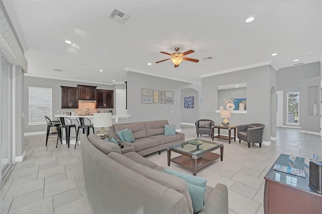 tiled living room with sink, crown molding, and ceiling fan