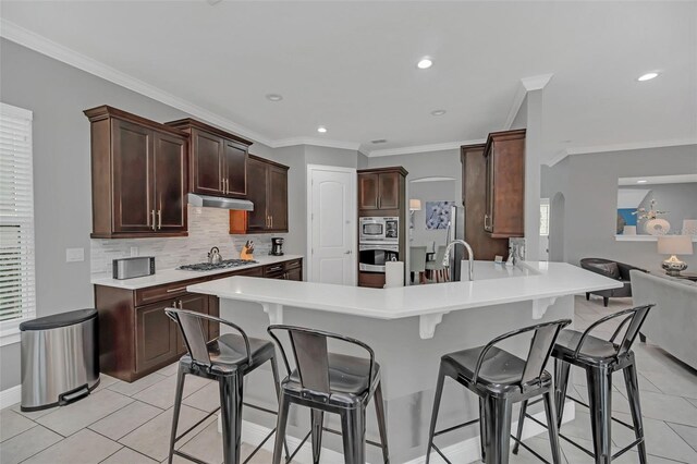 kitchen featuring light tile patterned flooring, appliances with stainless steel finishes, tasteful backsplash, crown molding, and a healthy amount of sunlight