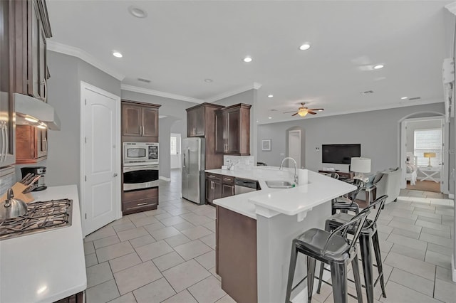 kitchen with sink, light tile patterned floors, a breakfast bar area, stainless steel appliances, and kitchen peninsula