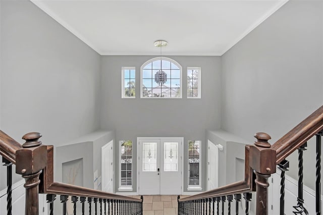 foyer entrance with tile patterned flooring, crown molding, a chandelier, and french doors