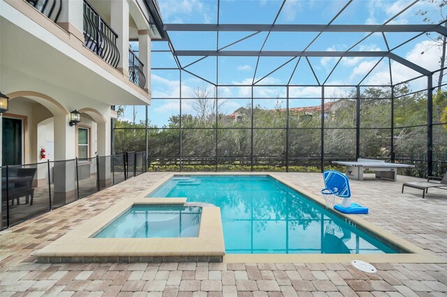 view of pool with a patio area, glass enclosure, and an in ground hot tub