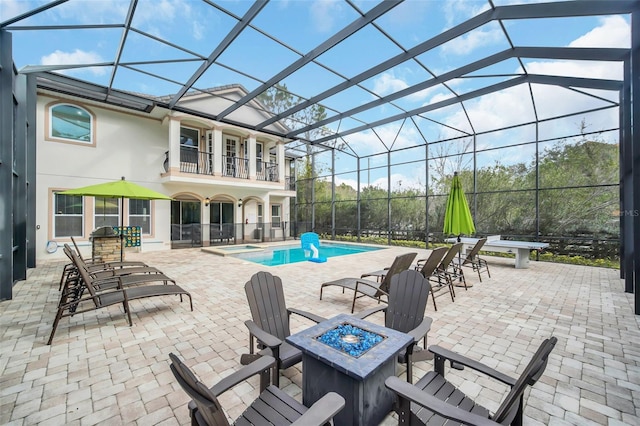 view of patio / terrace featuring a balcony, a lanai, and an outdoor fire pit