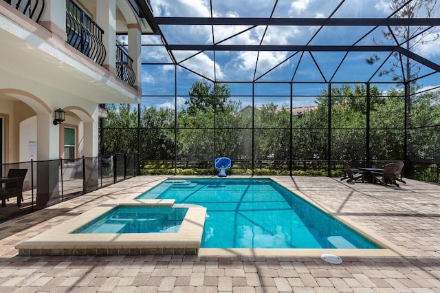 view of pool with a lanai, a patio area, and an in ground hot tub