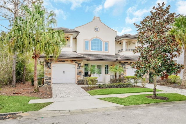 8162 Valhalla Ter, Reunion, FL 34747 - mediterranean / spanish-style house featuring driveway, an attached garage, a balcony, a front lawn, and stone siding