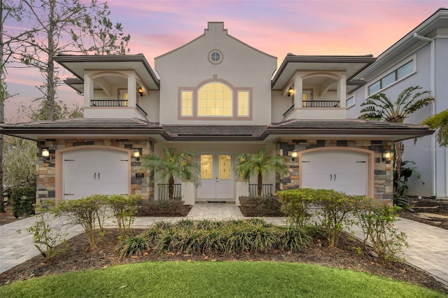 8162 Valhalla Ter, Reunion, FL 34747 - view of front of home featuring a balcony, a garage, driveway, and stone siding