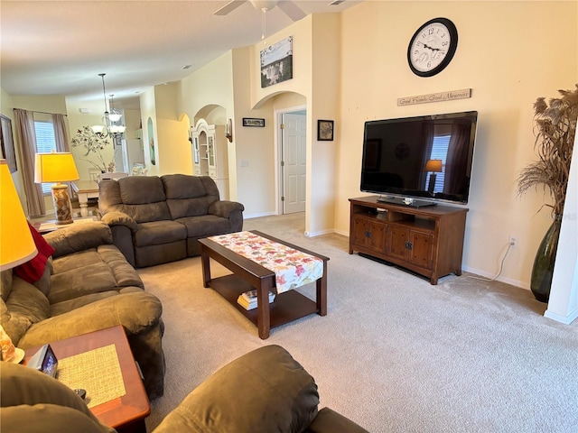 living room with ceiling fan with notable chandelier and light colored carpet