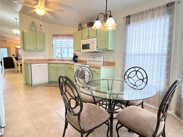 tiled dining area with ceiling fan with notable chandelier, sink, a wealth of natural light, and vaulted ceiling