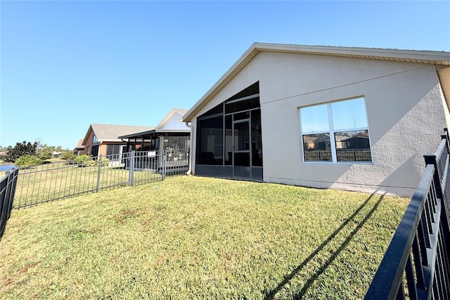 rear view of house with a yard and a sunroom