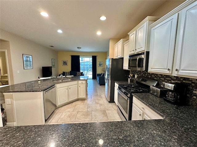 kitchen with appliances with stainless steel finishes, white cabinetry, sink, kitchen peninsula, and backsplash