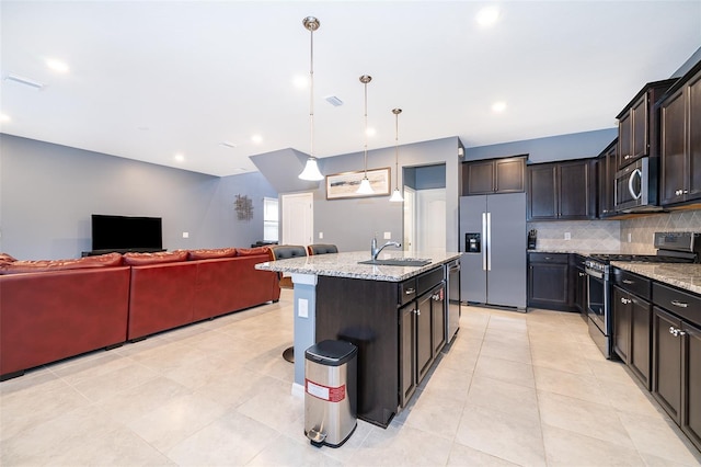 kitchen with tasteful backsplash, stainless steel appliances, sink, pendant lighting, and an island with sink