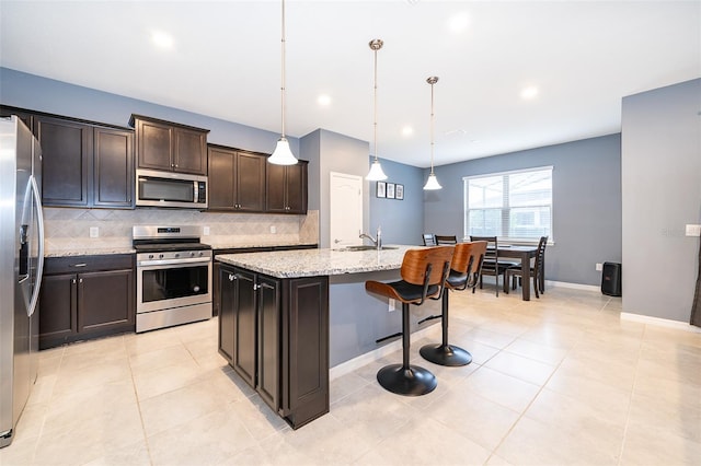 kitchen with sink, pendant lighting, a center island with sink, dark brown cabinets, and appliances with stainless steel finishes