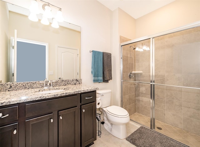 bathroom featuring tile patterned flooring, vanity, toilet, and an enclosed shower