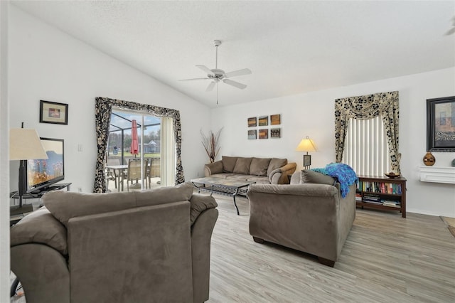 living room featuring ceiling fan, light wood-type flooring, a textured ceiling, and vaulted ceiling