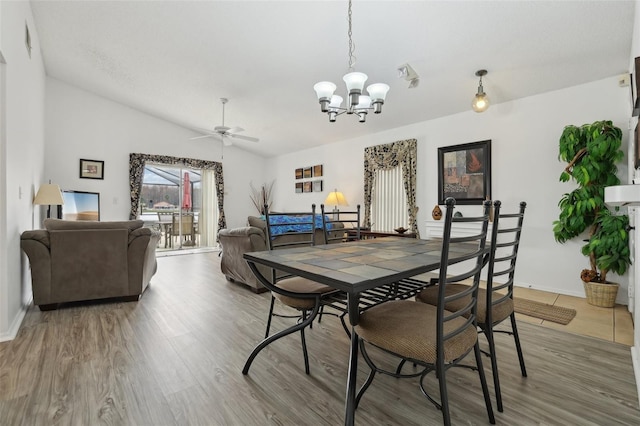 dining space with lofted ceiling, ceiling fan with notable chandelier, and hardwood / wood-style flooring