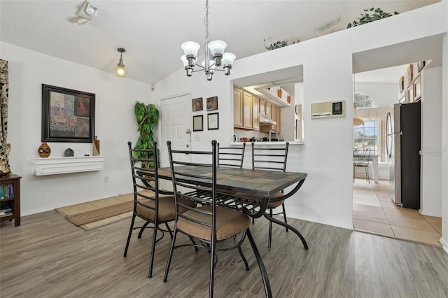 dining space featuring an inviting chandelier, lofted ceiling, and light hardwood / wood-style flooring