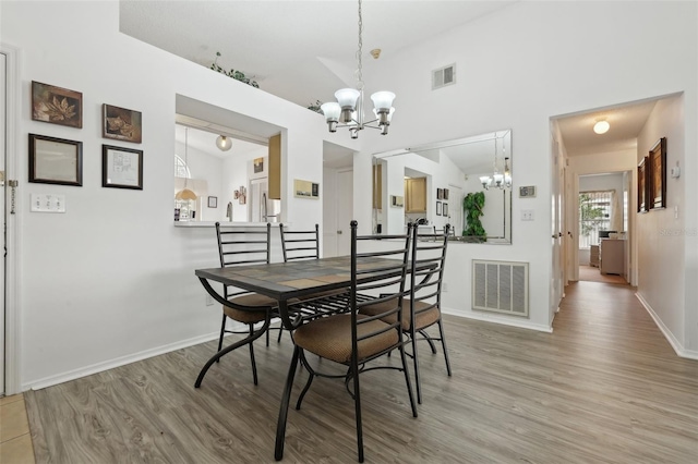 dining room with an inviting chandelier, light hardwood / wood-style flooring, and vaulted ceiling