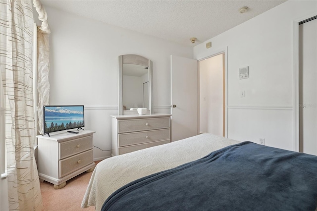 bedroom with light colored carpet and a textured ceiling