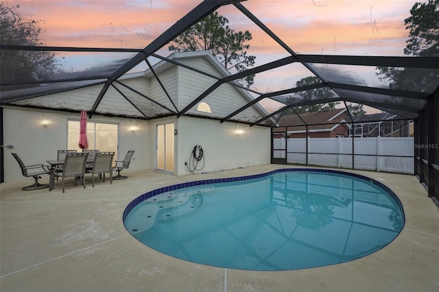 pool at dusk featuring a patio and glass enclosure