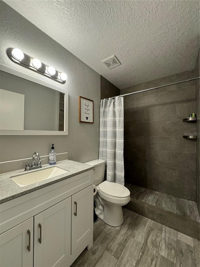 bathroom with a textured ceiling, toilet, vanity, and a shower with shower curtain