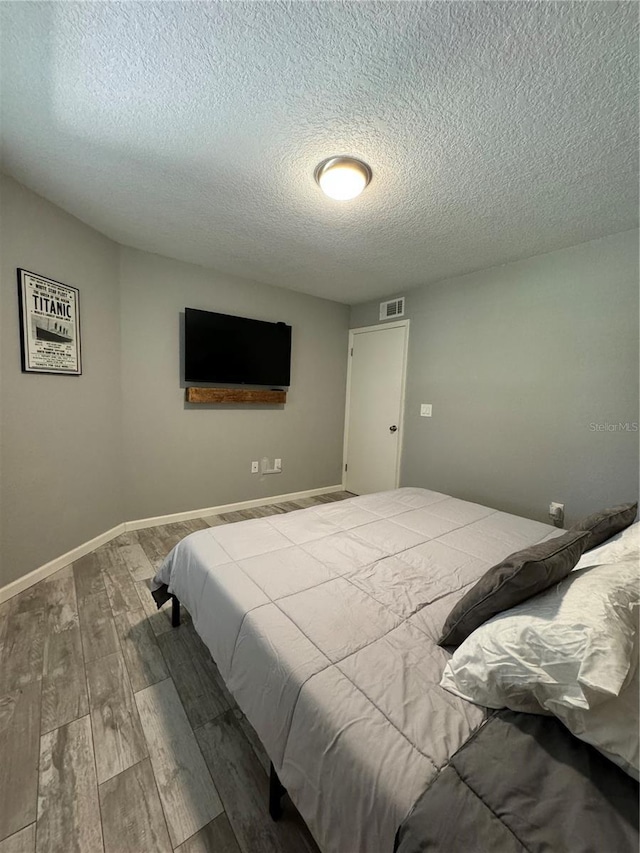 bedroom featuring hardwood / wood-style floors and a textured ceiling