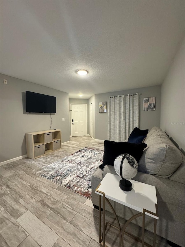 living room featuring light wood-type flooring and a textured ceiling