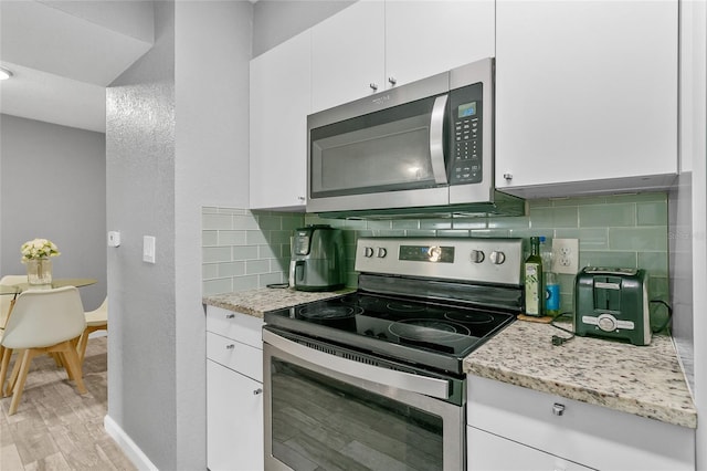 kitchen featuring stainless steel appliances, decorative backsplash, and white cabinetry