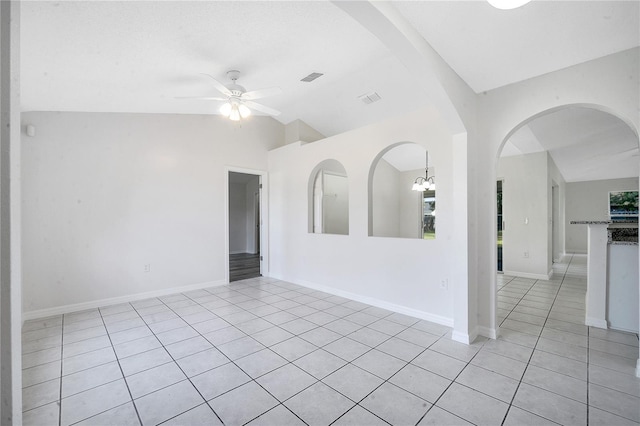 tiled empty room with vaulted ceiling and ceiling fan with notable chandelier