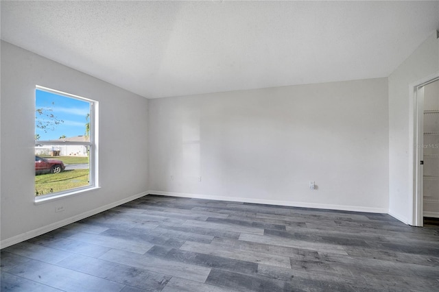 spare room with a textured ceiling and dark hardwood / wood-style floors