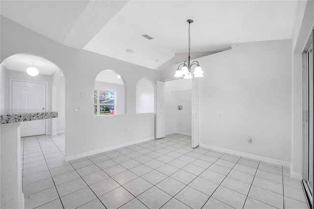 unfurnished room featuring a chandelier, light tile patterned floors, a textured ceiling, and vaulted ceiling