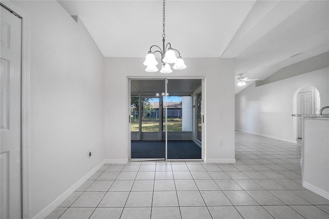 unfurnished dining area with ceiling fan with notable chandelier, light tile patterned floors, and vaulted ceiling