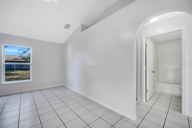 tiled empty room featuring vaulted ceiling