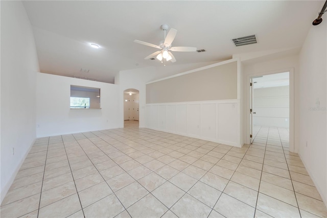 empty room featuring ceiling fan, light tile patterned floors, and vaulted ceiling