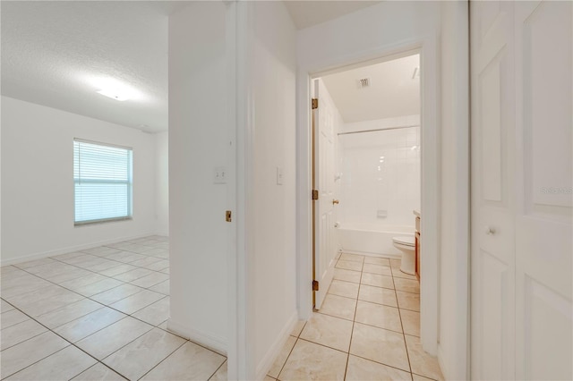 hall featuring light tile patterned floors and a textured ceiling