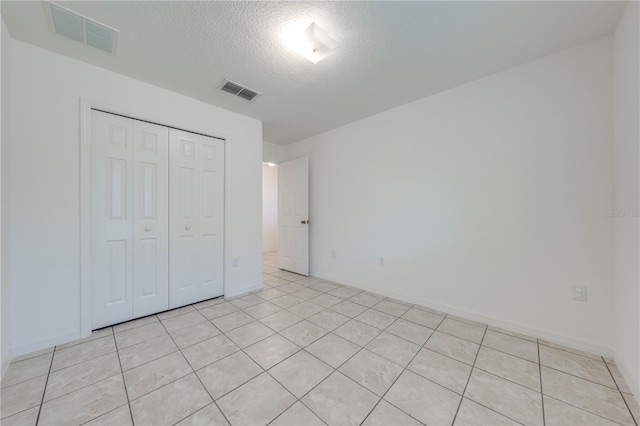 unfurnished bedroom with light tile patterned floors, a textured ceiling, and a closet