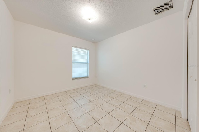 empty room with light tile patterned floors and a textured ceiling