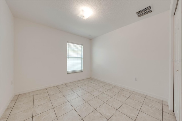 unfurnished room with light tile patterned floors and a textured ceiling