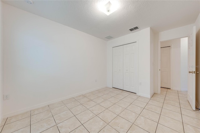 unfurnished bedroom with a closet, light tile patterned floors, and a textured ceiling