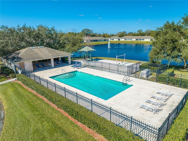 view of swimming pool featuring a lawn, a patio area, and a water view