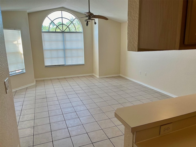 unfurnished dining area with vaulted ceiling, ceiling fan, and light tile patterned flooring