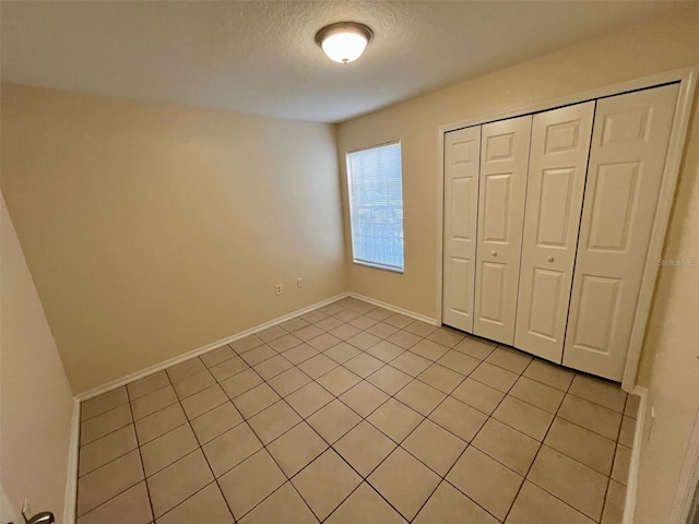 unfurnished bedroom with a textured ceiling, a closet, and light tile patterned flooring