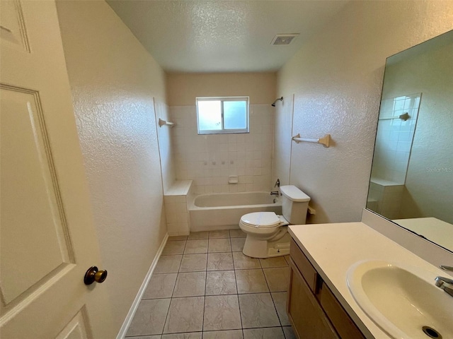 full bathroom with vanity, tile patterned floors, tiled shower / bath, toilet, and a textured ceiling