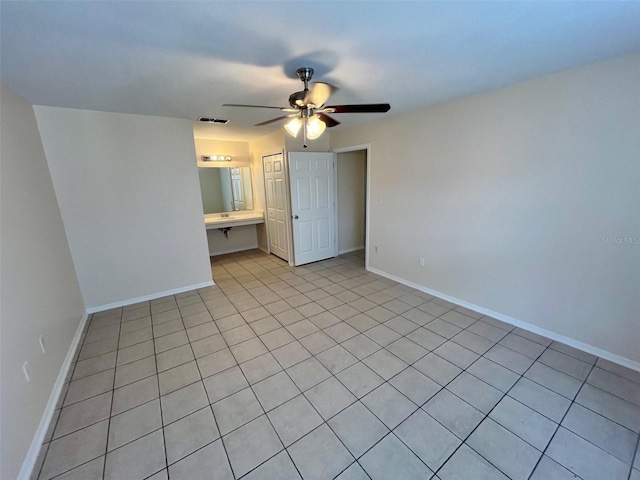 unfurnished bedroom featuring ensuite bath, ceiling fan, and light tile patterned floors