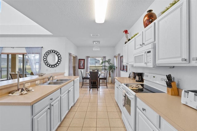 kitchen with a textured ceiling, white appliances, sink, white cabinets, and light tile patterned flooring