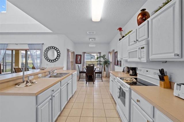 kitchen with white appliances, sink, a textured ceiling, light tile patterned flooring, and white cabinetry