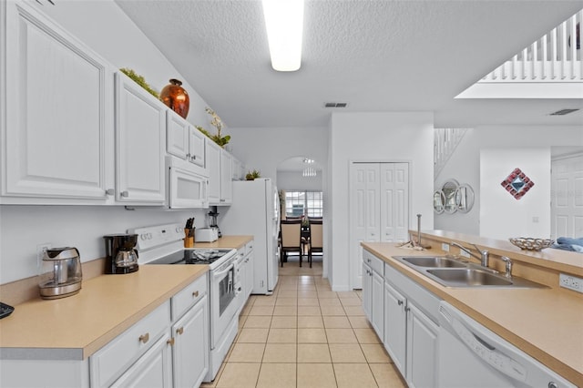 256 Lancaster Dr, Davenport, FL 33897 - kitchen featuring white appliances, arched walkways, light tile patterned floors, white cabinetry, and a textured ceiling