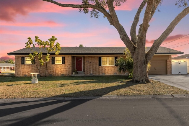 ranch-style house featuring a garage and a lawn