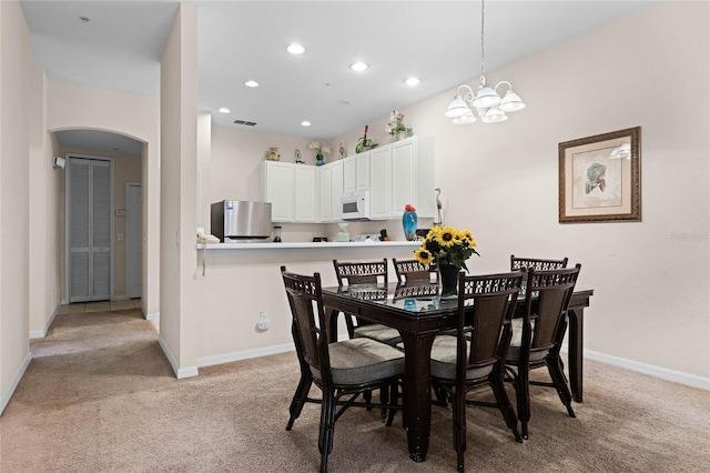 dining area featuring a notable chandelier and light colored carpet