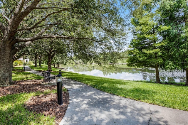 view of property's community with a water view and a lawn