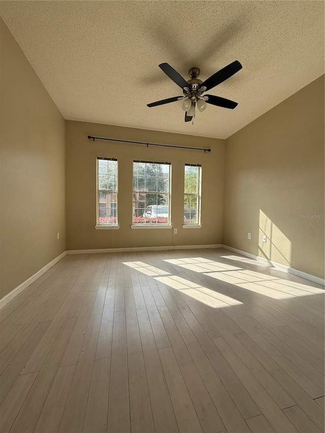 unfurnished room with ceiling fan, light hardwood / wood-style flooring, a textured ceiling, and plenty of natural light